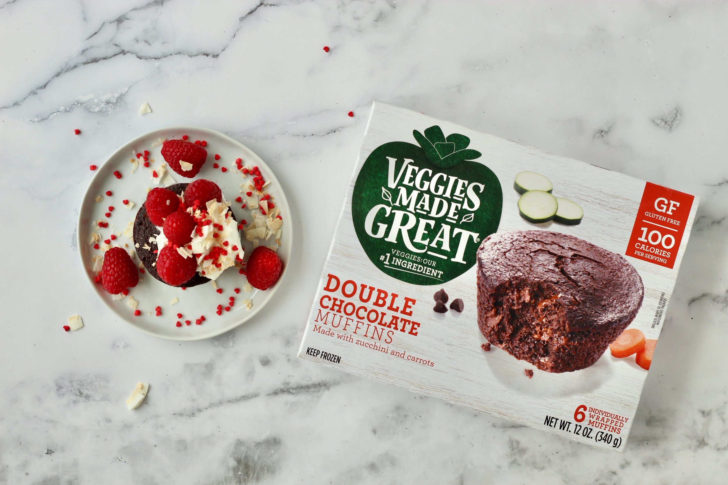 double chocolate muffins box next to plate with whipped cream and raspberries on chocolate muffin