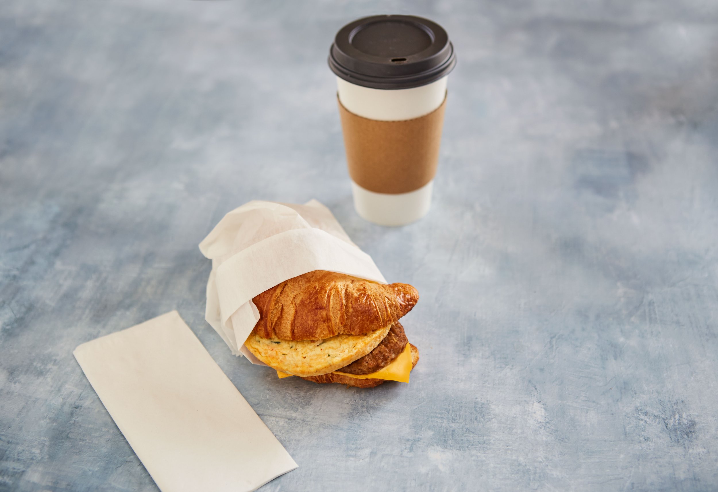 breakfast croissant sandwich with coffee