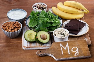 Uma coleção de alimentos ricos em magnésio, incluindo abacates, bananas, amêndoas, chocolate amargo, espinafre. O magnésio aumenta os níveis de oxitocina no cérebro.