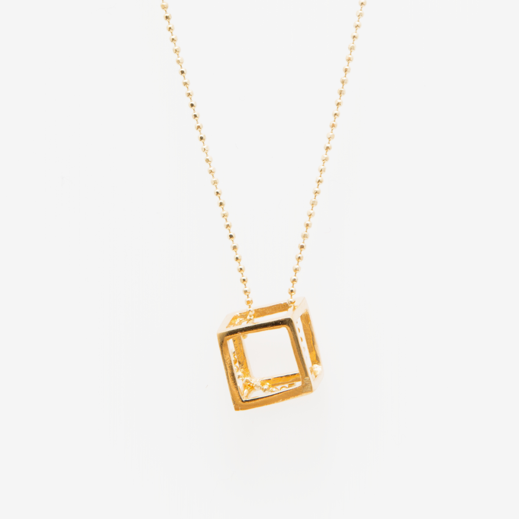 small gold cube on a gold chain