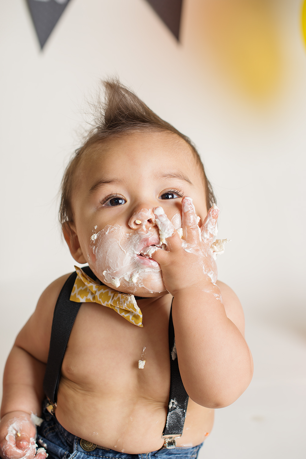 Cute baby with cake on his face during a milestone baby cake smash session