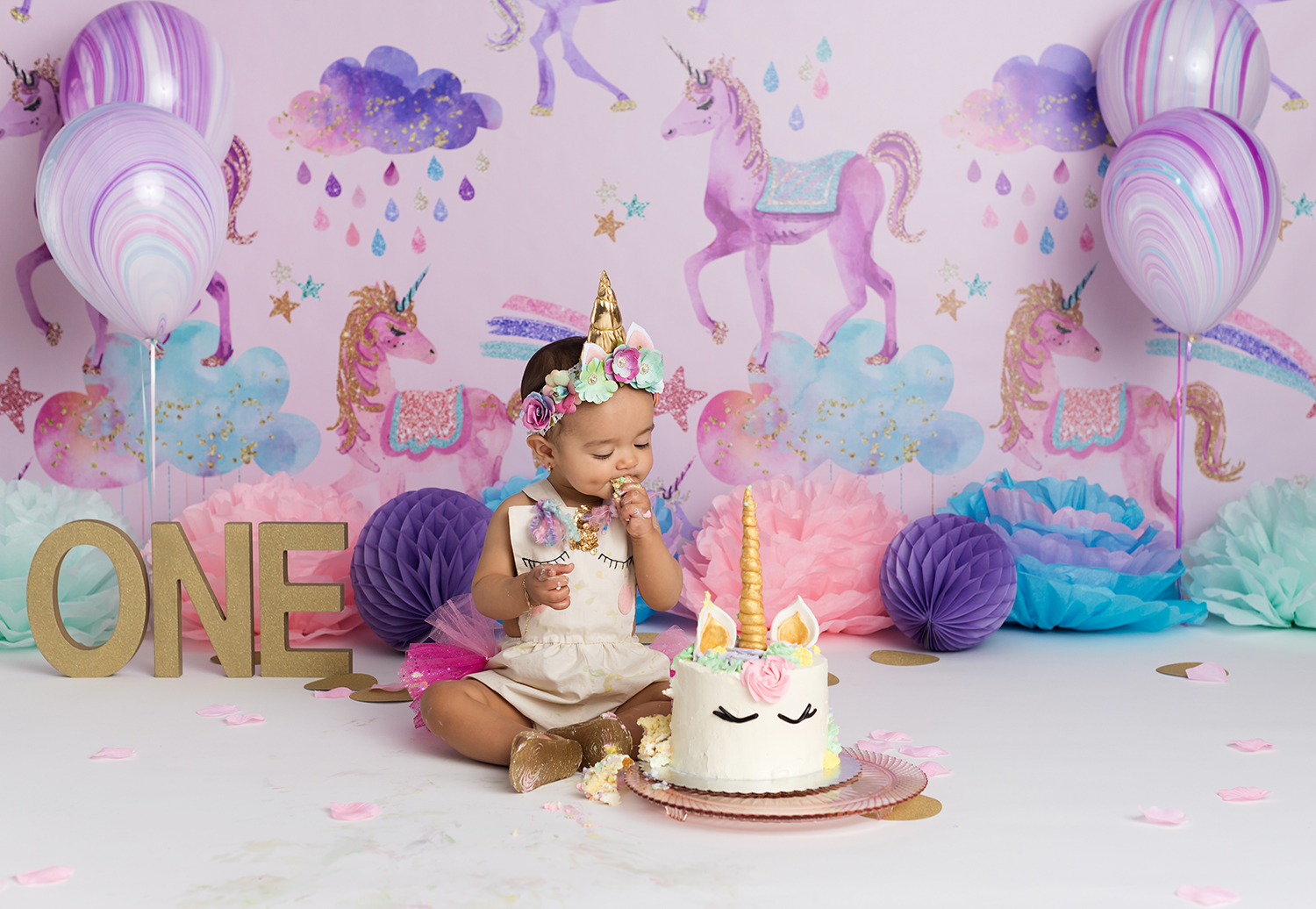 studio first birthday cake smash of baby girl and unicorn theme setup
