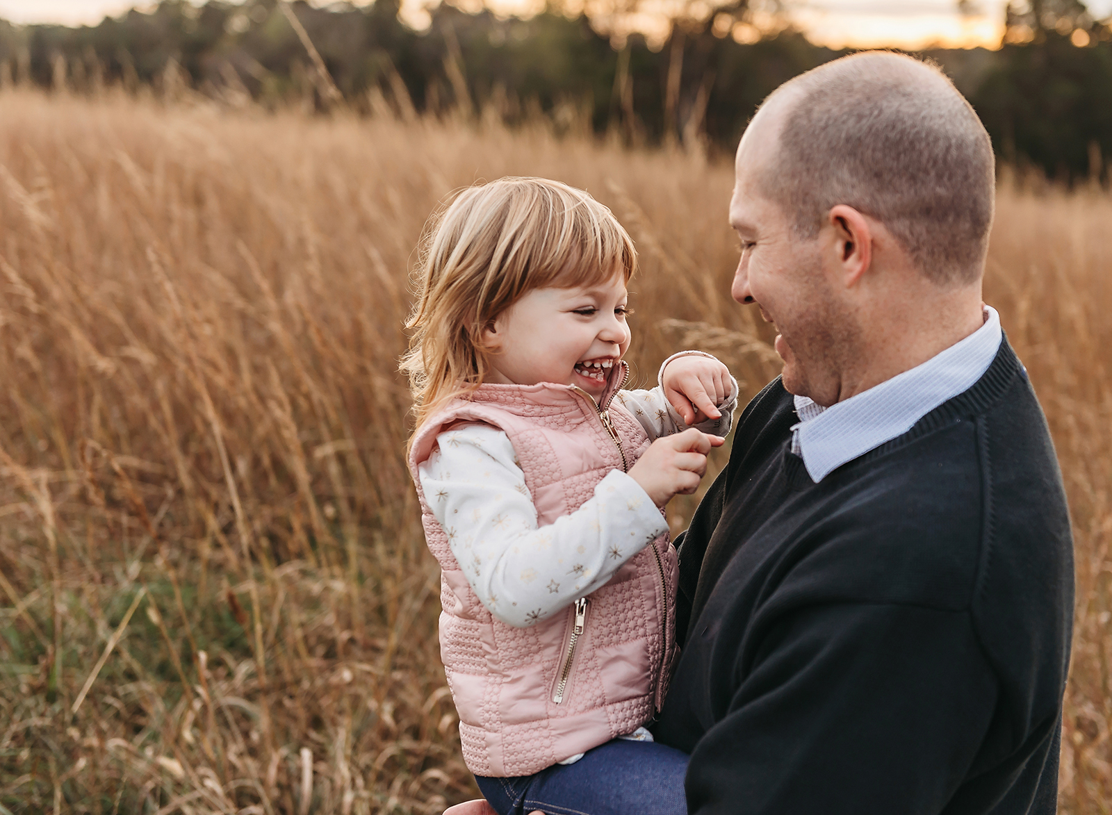 dad and daughter laughing in a tall grass field.jpg