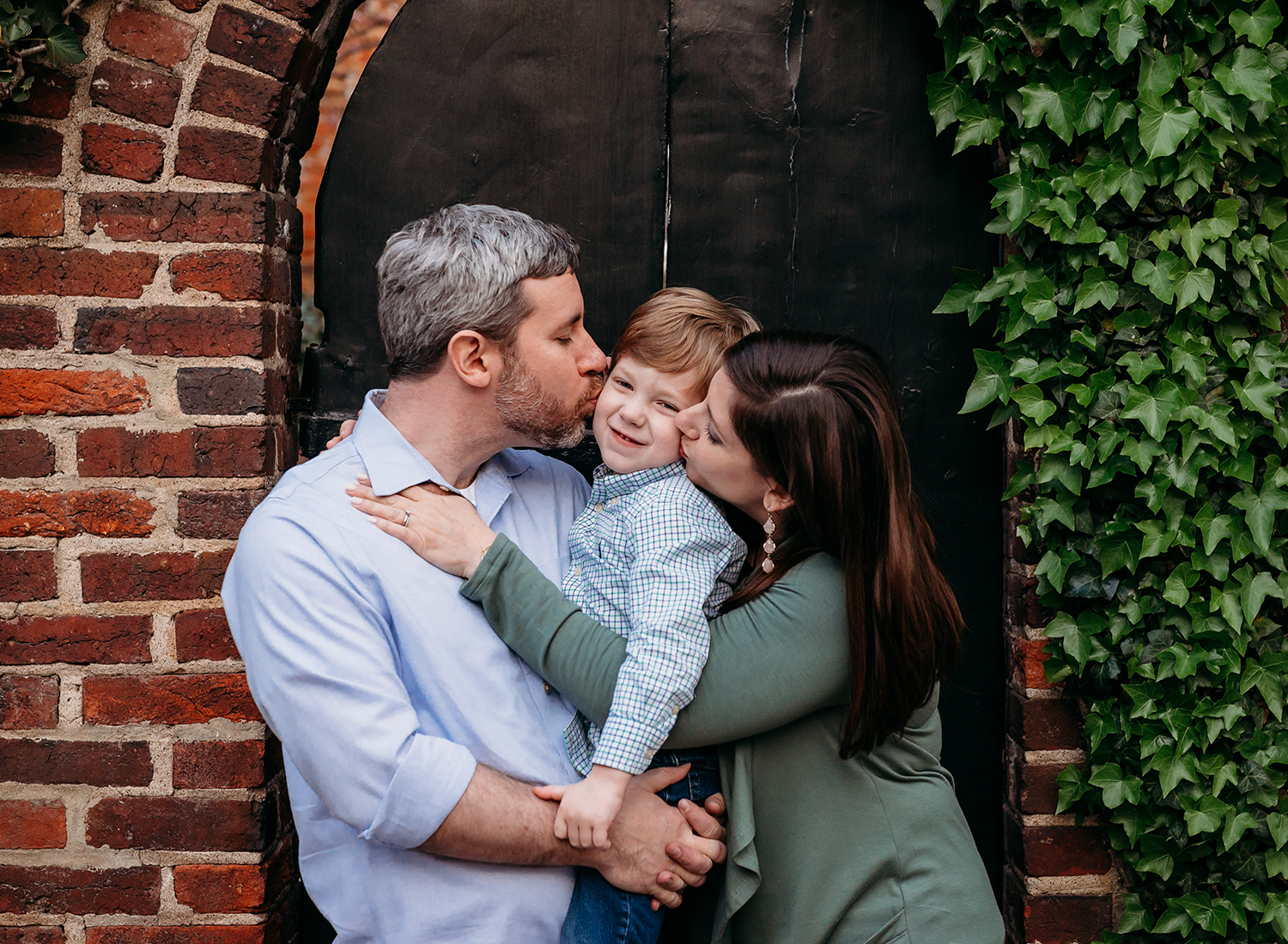 downtown family spring session of parents kissing their son
