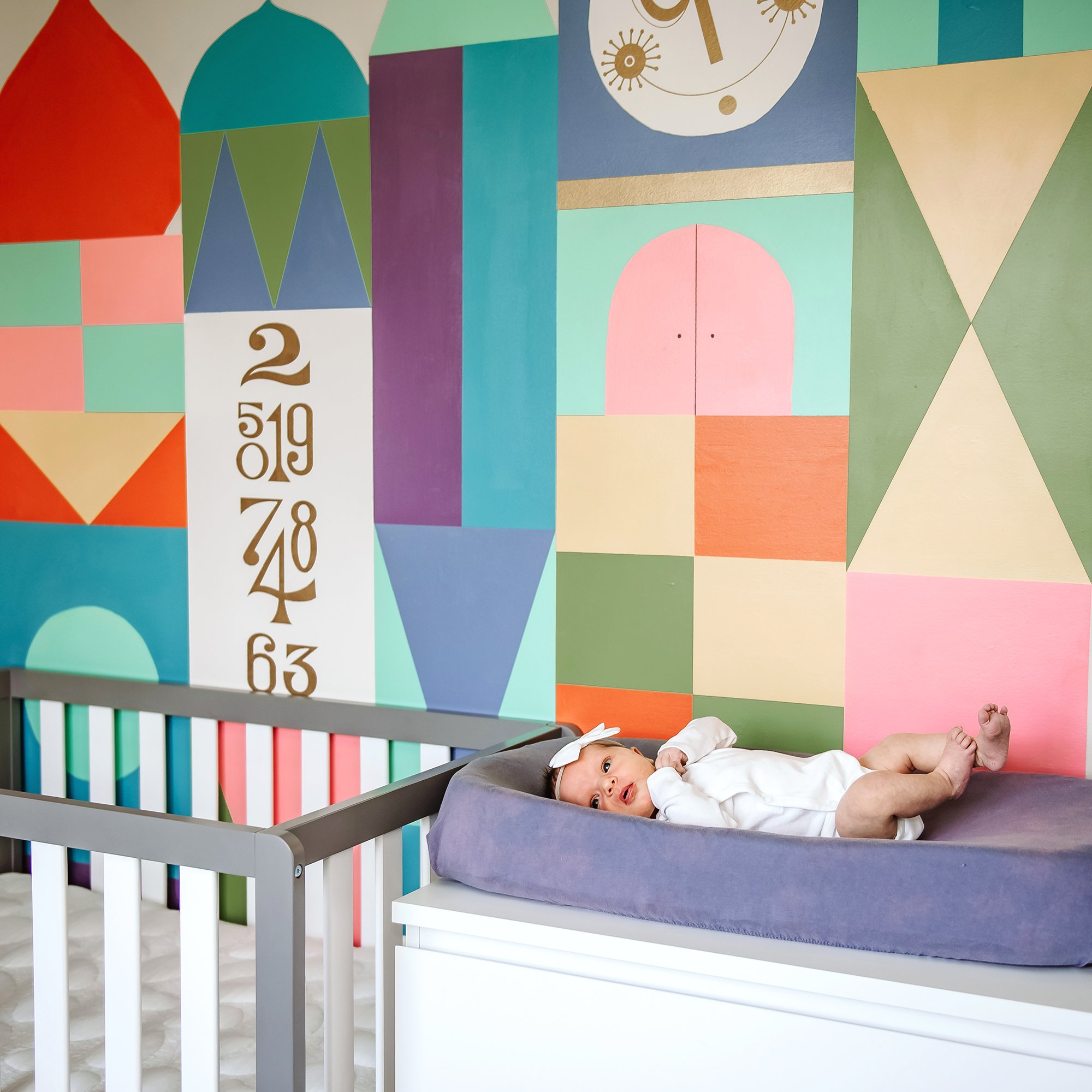 painted mural in nursery with newborn on changing table.jpg
