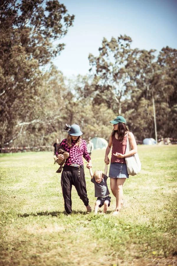 Two women walk in a field with a child in between in a field.jpg