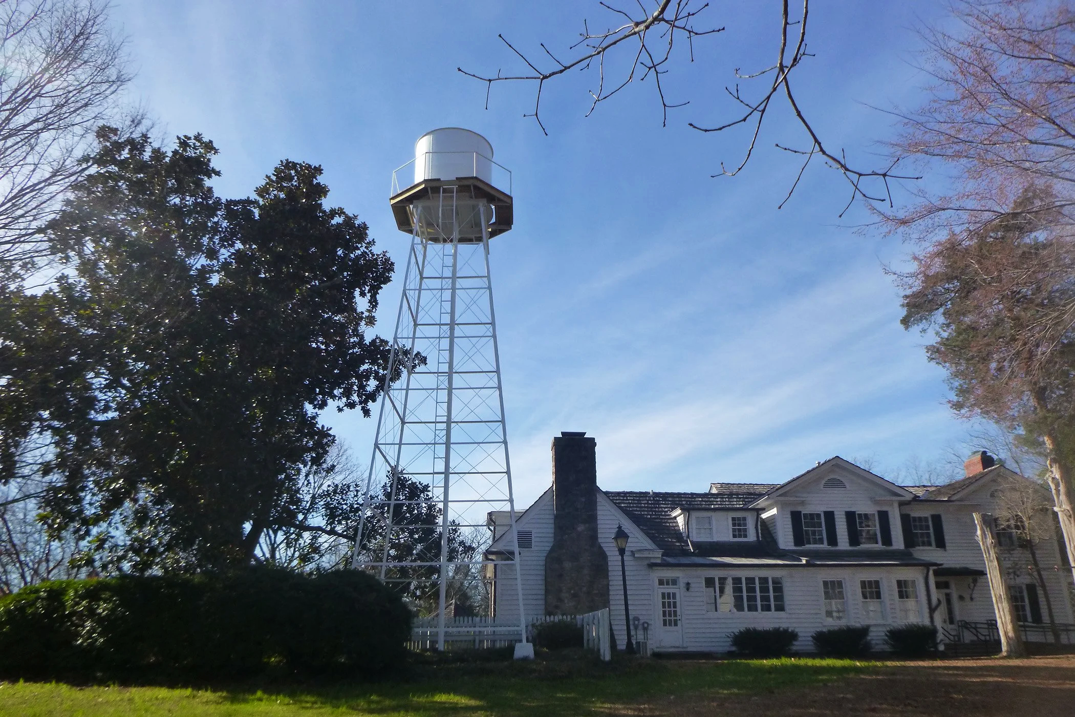 A white watertower beside a large white house