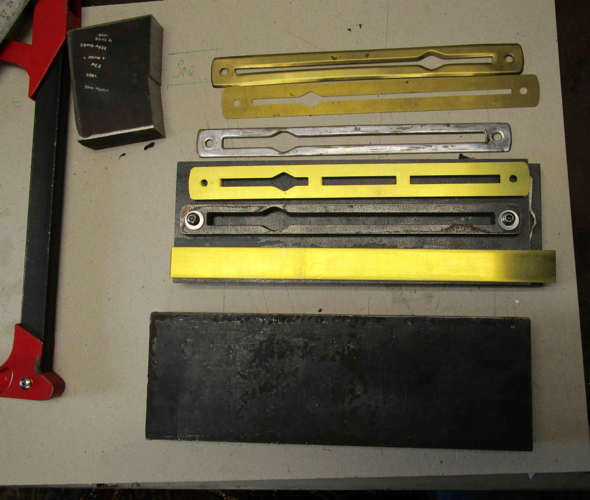 Tooling and laser cut brass .025" (0.64mm) escutcheon plate blank. At top first trial using rubber hydroforming method.