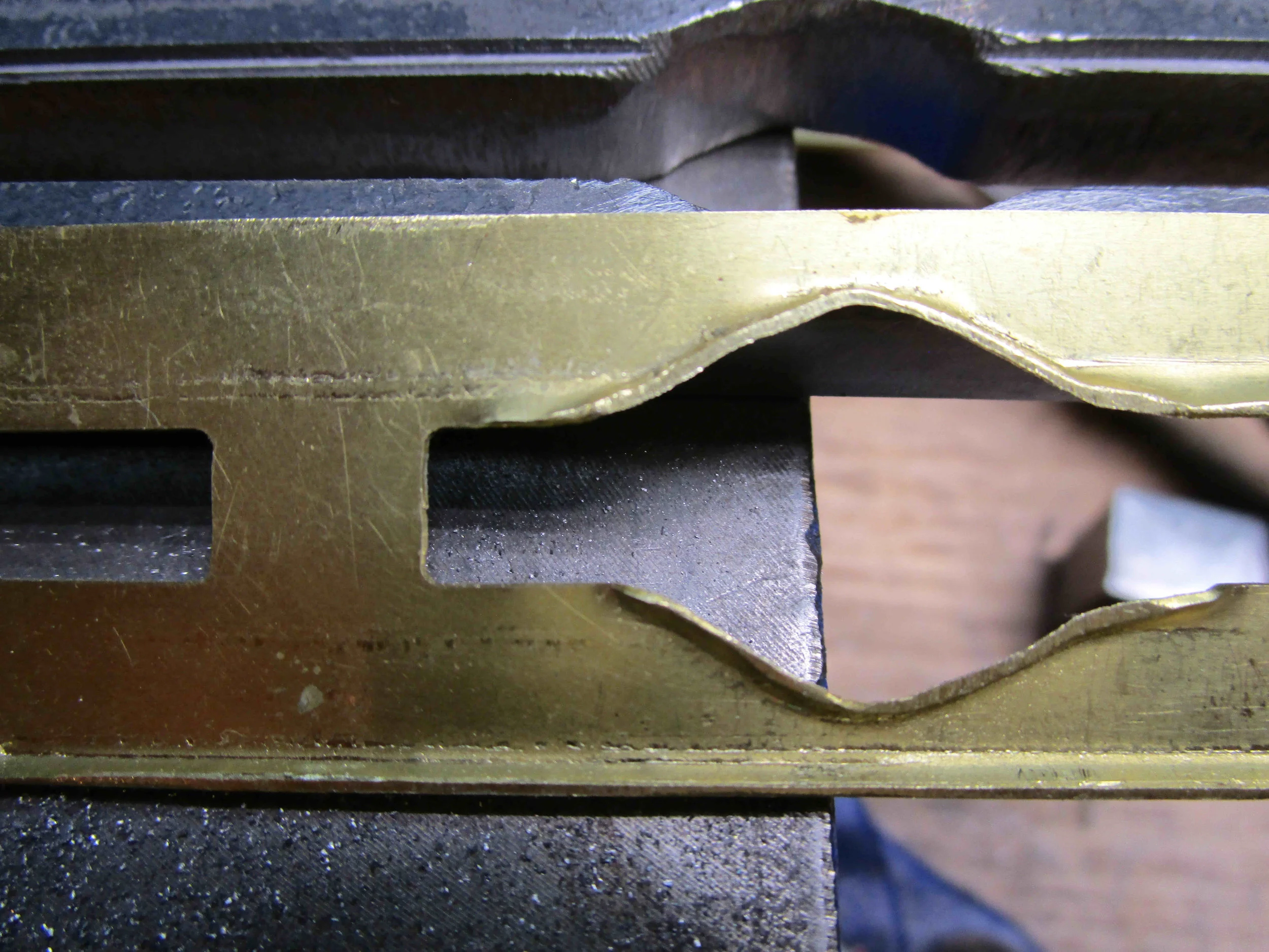 Folding detail taking shape of formed escutcheon plate. Top remains flat, and tabs ensure plate retains correct size. 