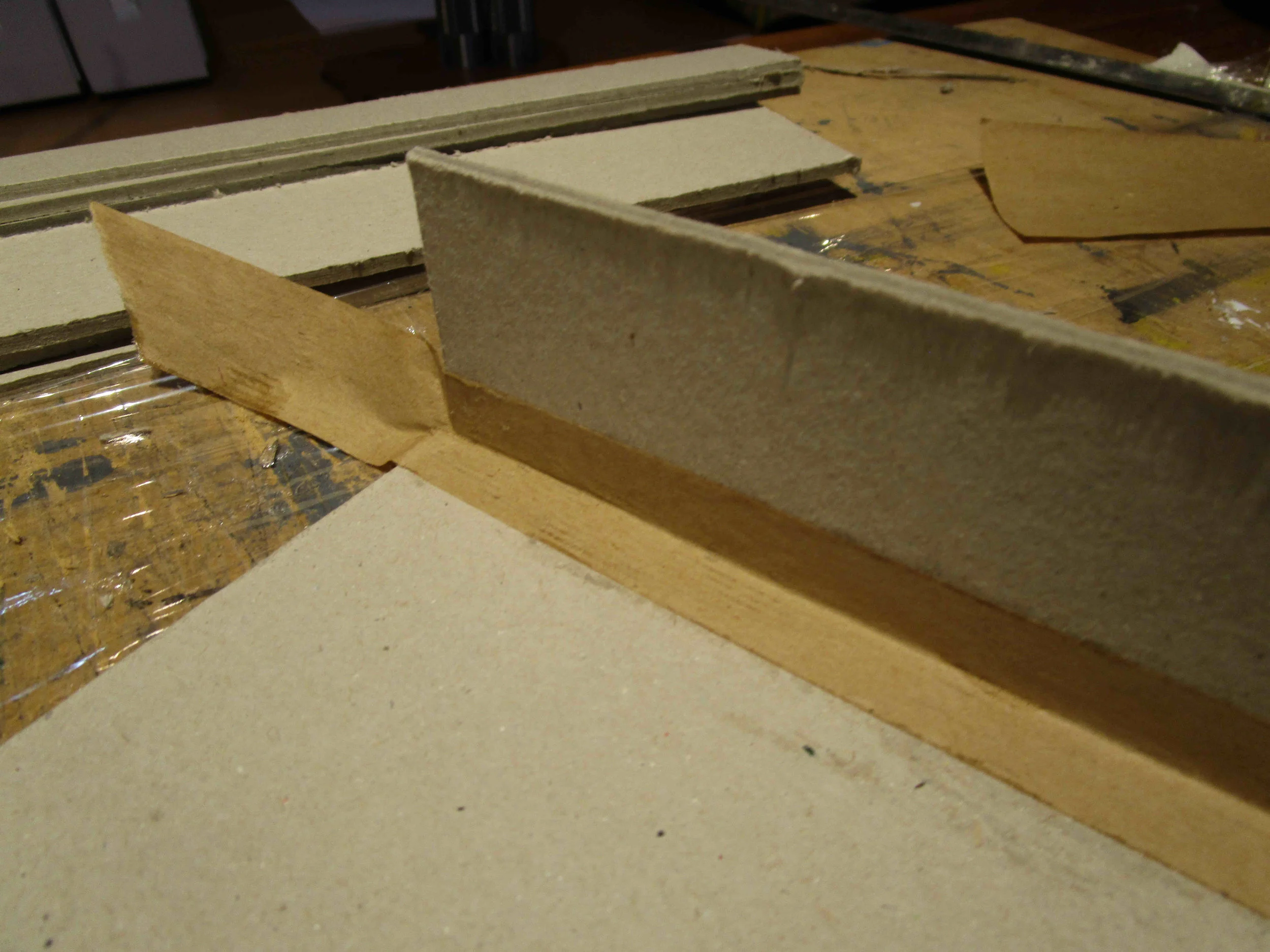 Align side to base, and leave a 3mm gap. Adher book repair acid free tape to outside first. Brush in industrial cross-linking PVA glue in to the gap before lifting the side square. Tape inside.&nbsp; &nbsp;