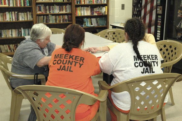 On a Friday afternoon in mid-April, Jayne Otley and Carol Schumacher visit with two inmates in the Meeker County Jail library. A pair of Encouragement Klatch Ministry volunteers meets with female inmates at the facility weekly. Part of the shared ex…