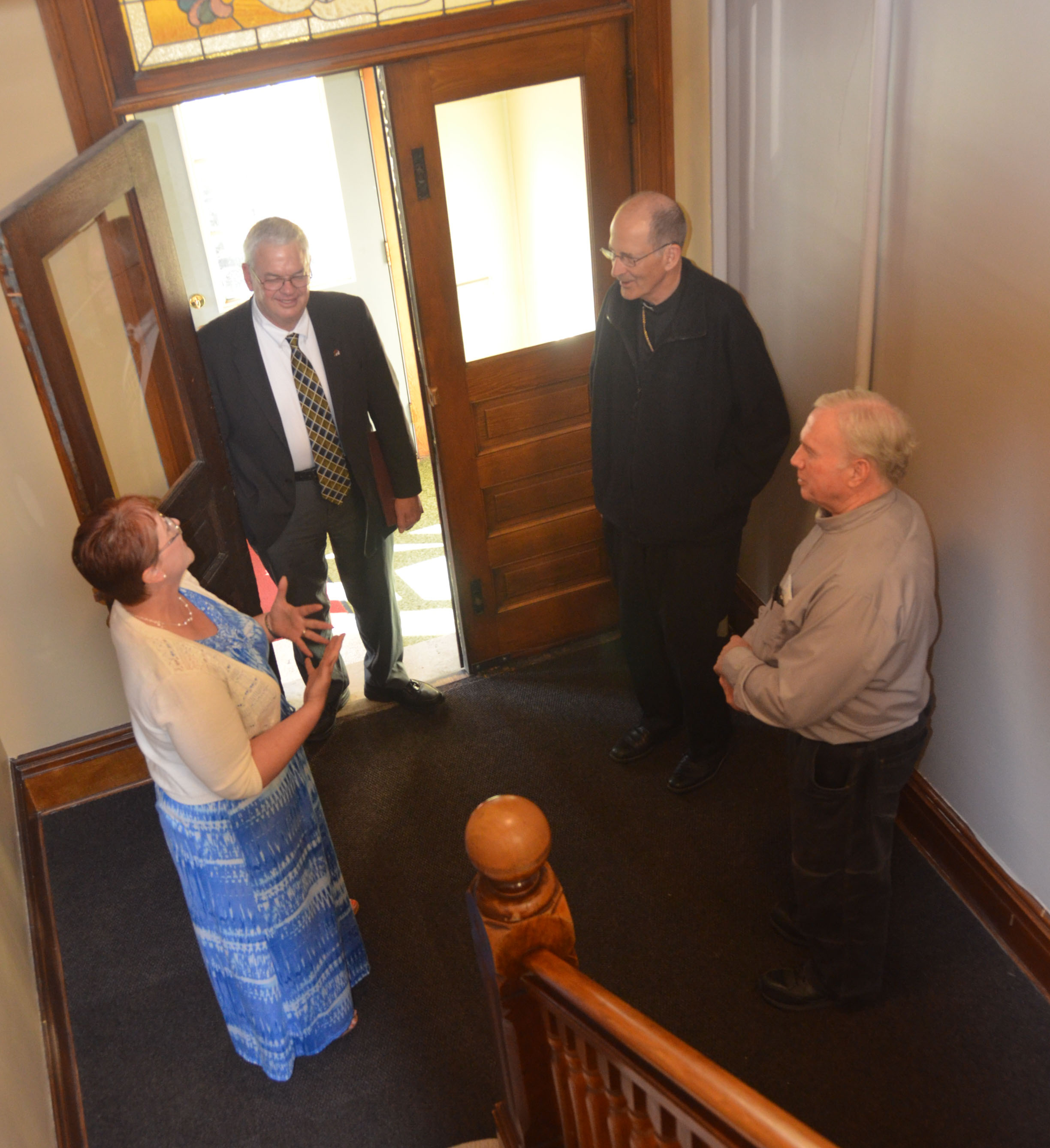 NUMAS Haus Shelter Coordinator Patty Paulson converses in the foyer with Tom Keaveny (left), director of Catholic Charities for the Diocese of New Ulm; Bishop John M. LeVoir; and Deacon Tim Dolan, director of Social Concerns for the diocese and NUMAS Haus board member, during a visit to the house June 21. (Photo by Christine Clancy)