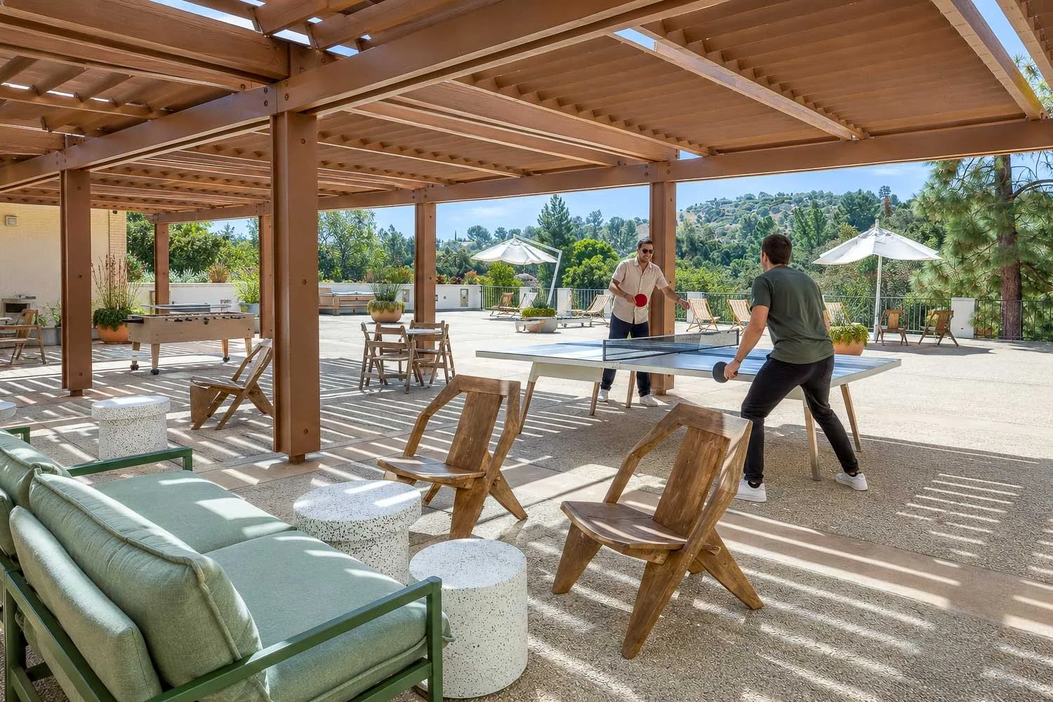 Two people playing table tennis on a covered outdoor terrace at The Park Calabasas.