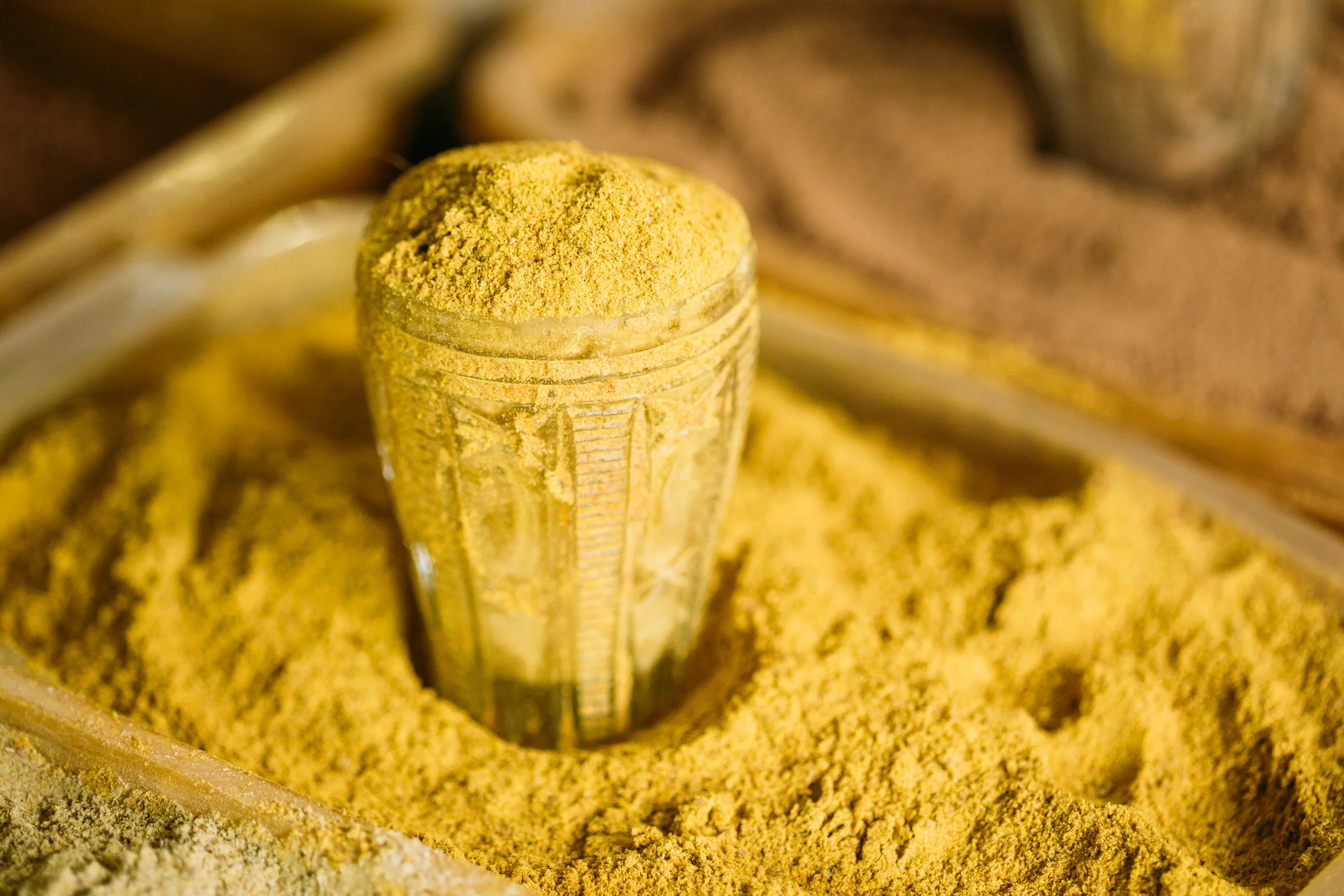 close-of-turmeric-powder-in-glass-in-heap-of-PFKJGJM.jpg