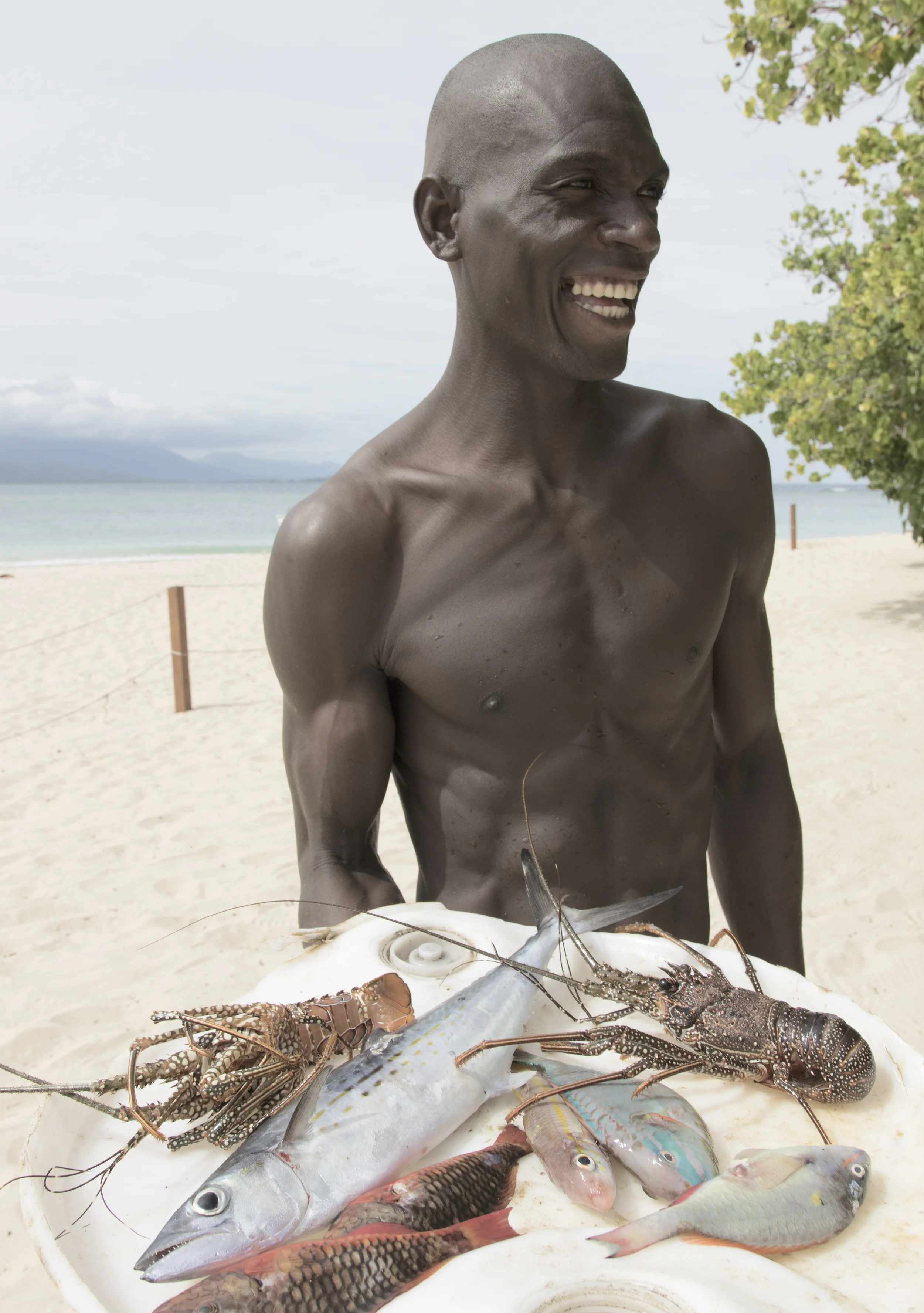 A FISHERMAN SHOWS OFF HIS CATCH AT AMIGA ISLAND, NORTHERN HAITI.