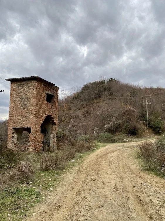  A crumbling brick building next to the path. 