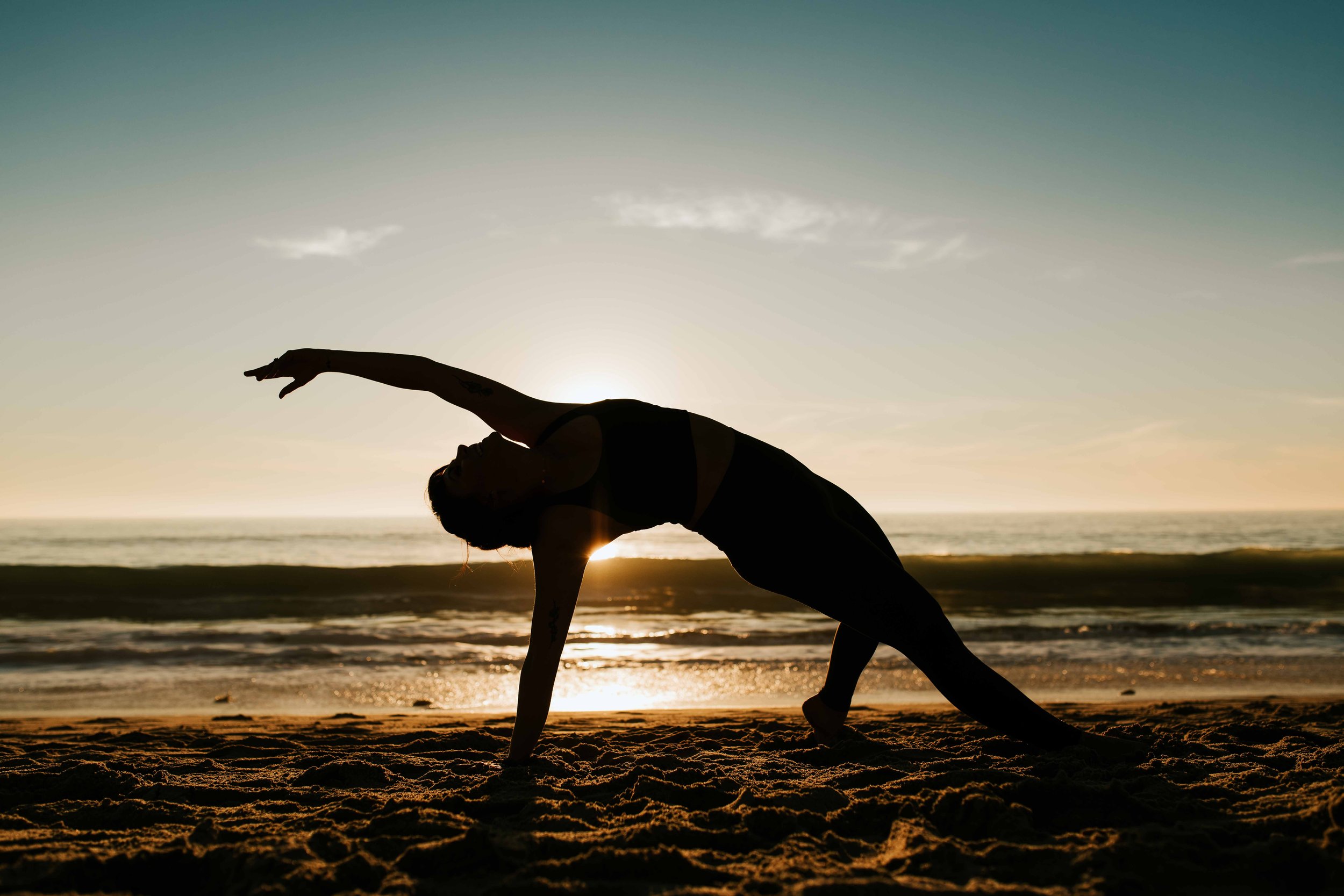  Young women practice yoga poses on San Clemente State Beach for a photoshoot 