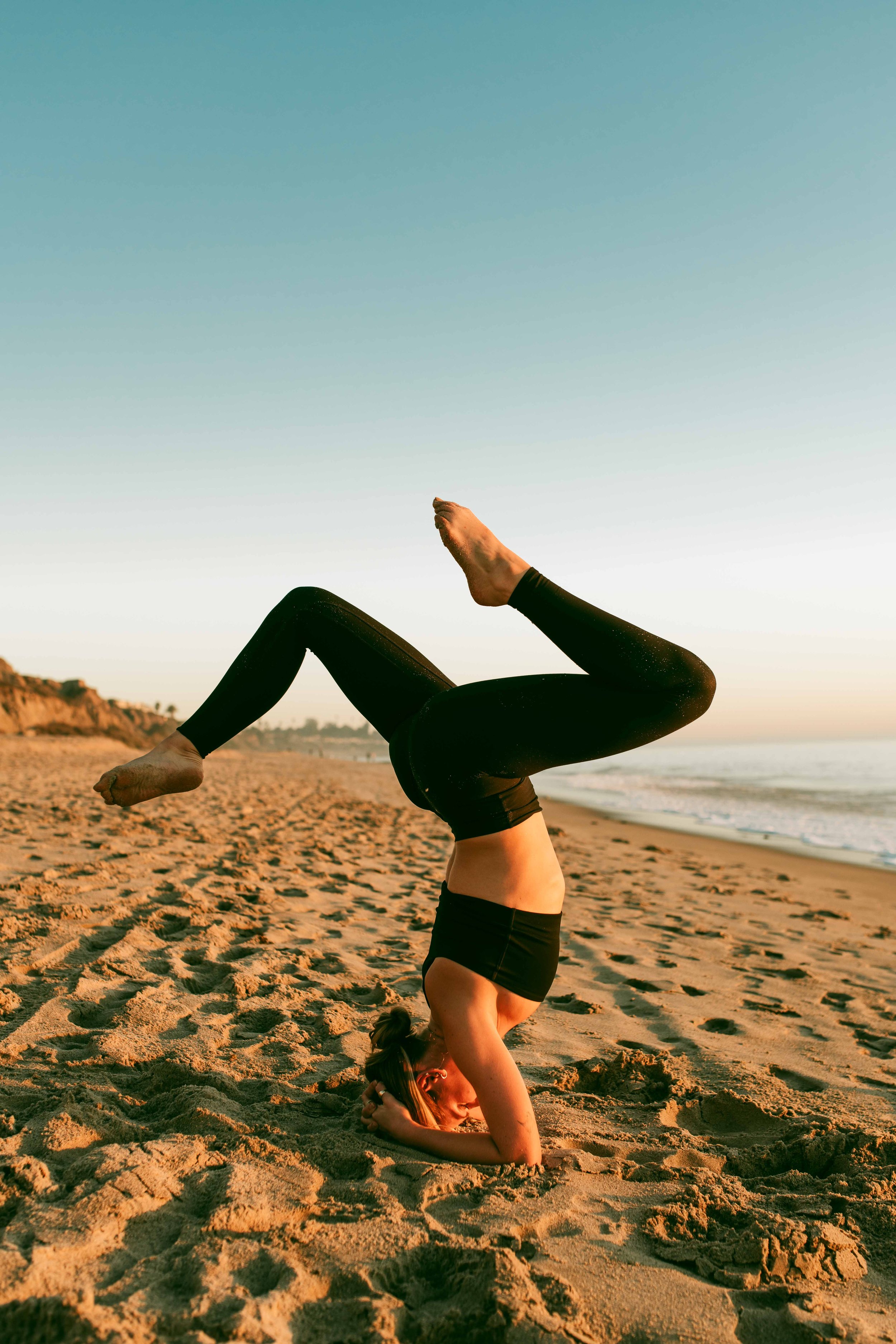  Young women practice yoga poses on San Clemente State Beach for a photoshoot 