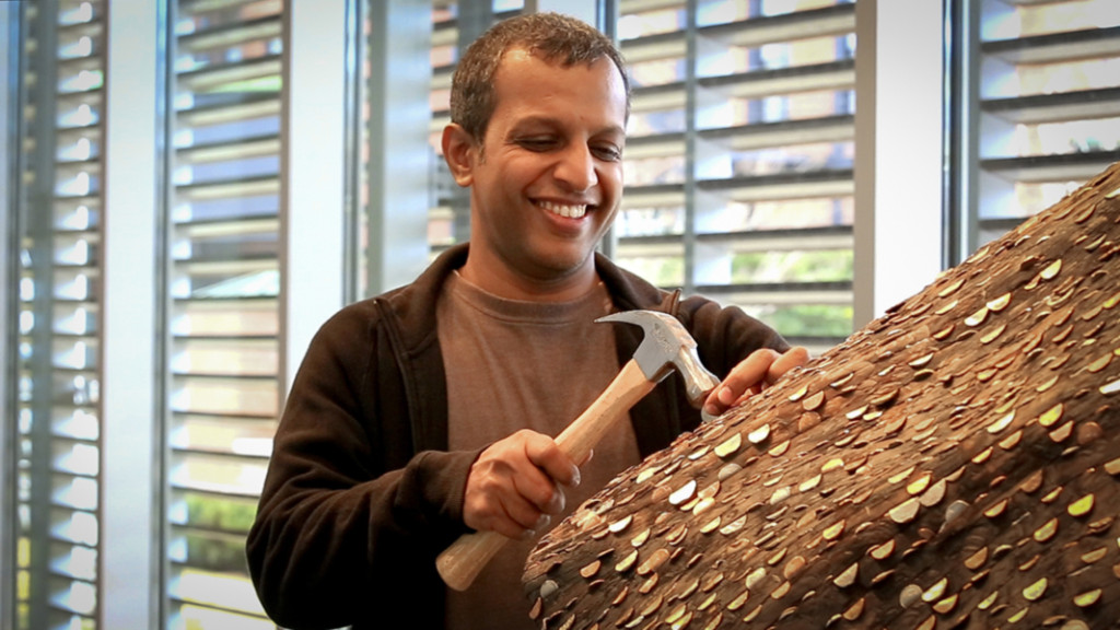 Tallur L. N. hammering a coin into his piece, “Chromathophobia.”