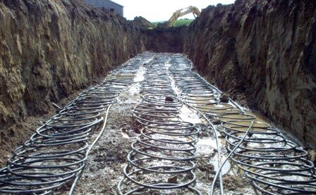 A three-ton slinky loop prior to being covered with soil. The three slinky loops are running out horizontally with three straight lines returning the end of the slinky coil to the heat pump. Photo by Mark Johnson