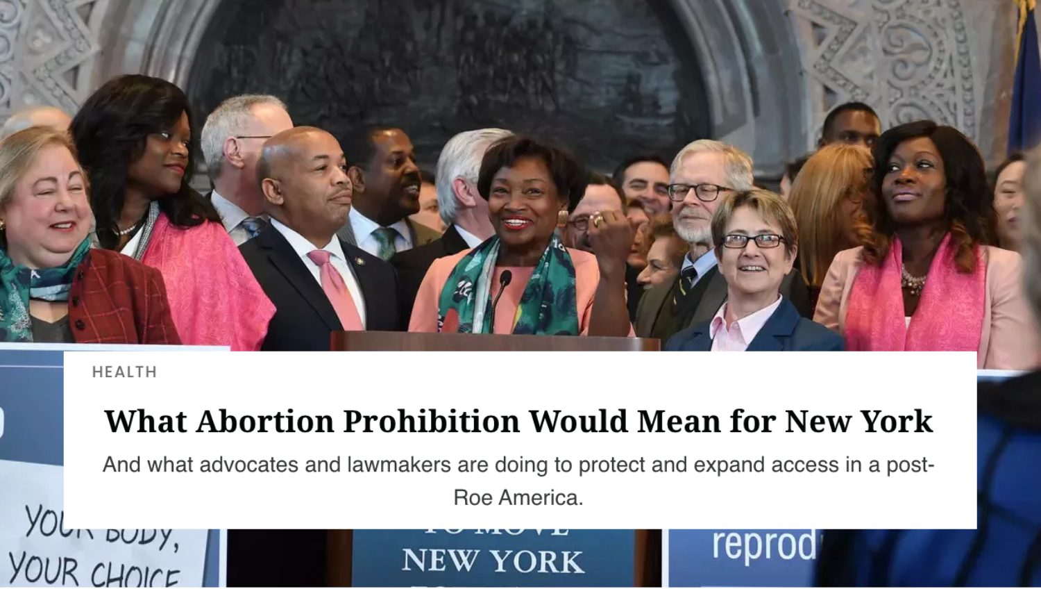 A group of people gathered at a podium, smiling, with Andrea Stewart Cousins in the center, at an event discussing abortion laws in New York. A white text box reads Chronogram headline,  "What Abortion Prohibition Would Mean for New York"