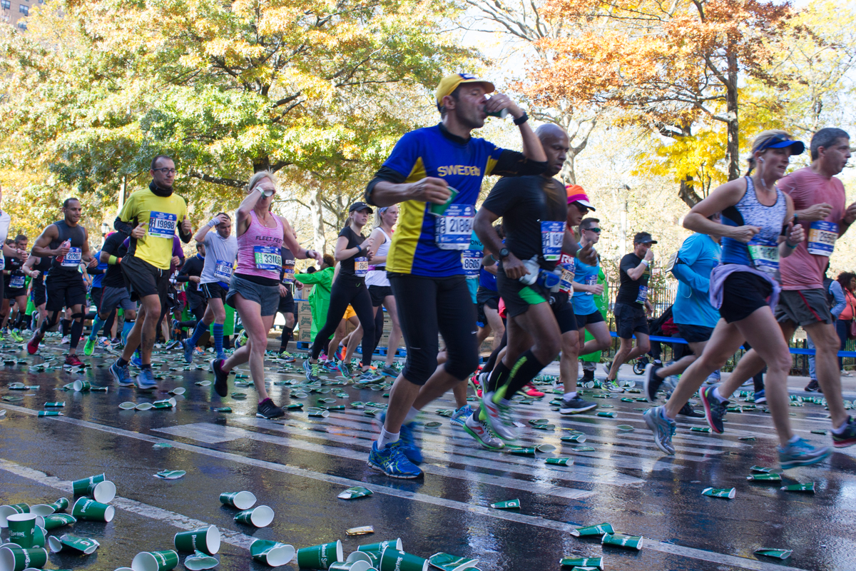 Runners drinking beverages on the go throw their finished cups to the floor.