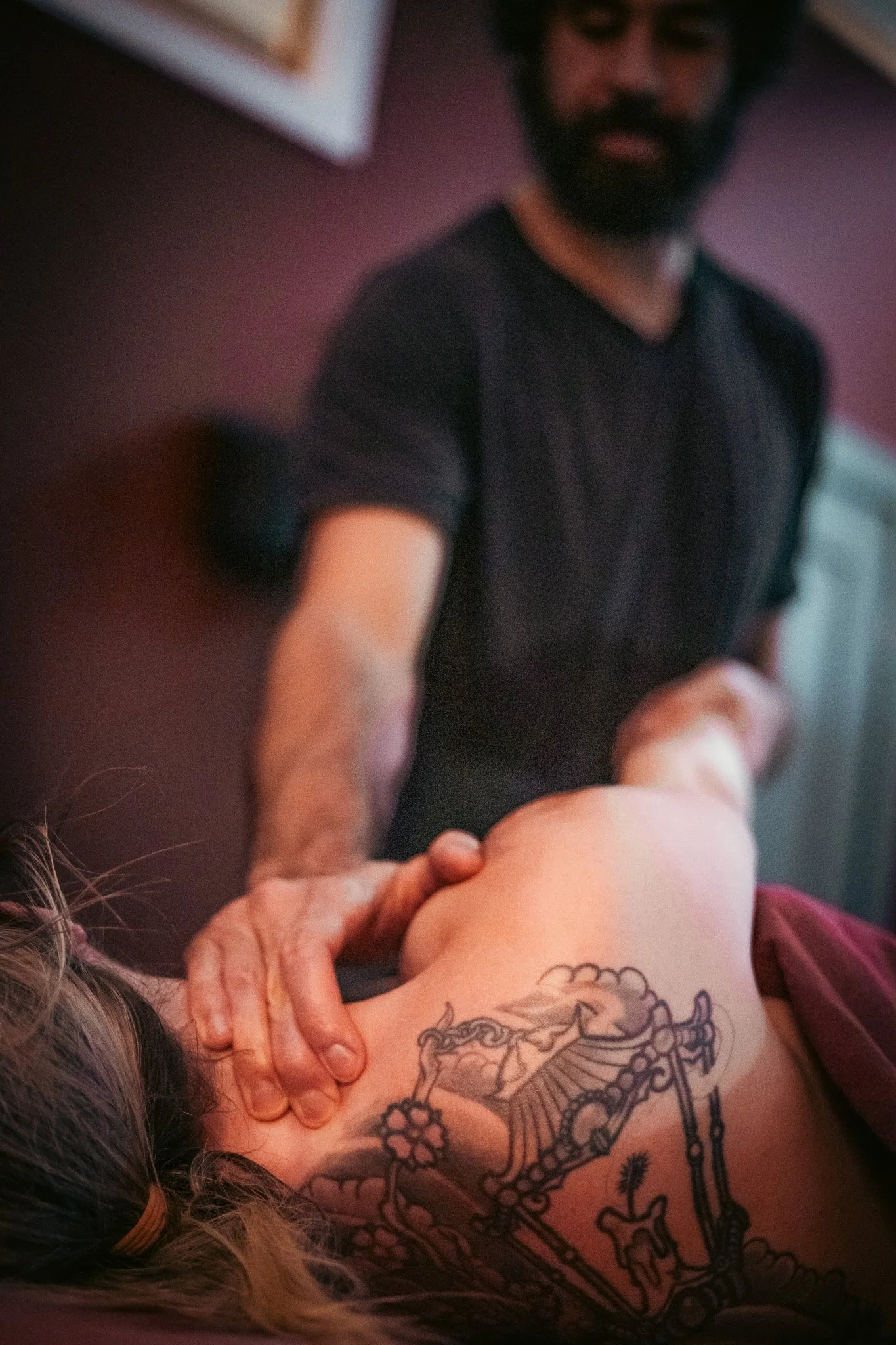 Person receiving a back massage with tattoo visible.