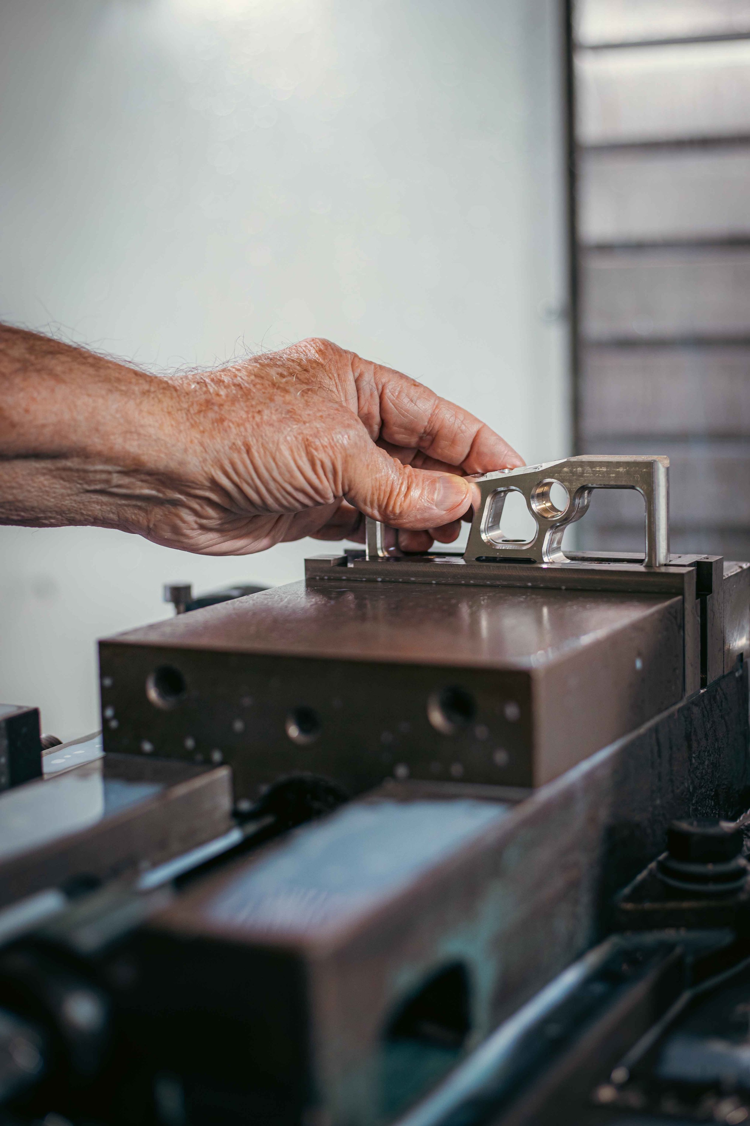 A person's hand placing a metal part into a machine for machining or inspection.