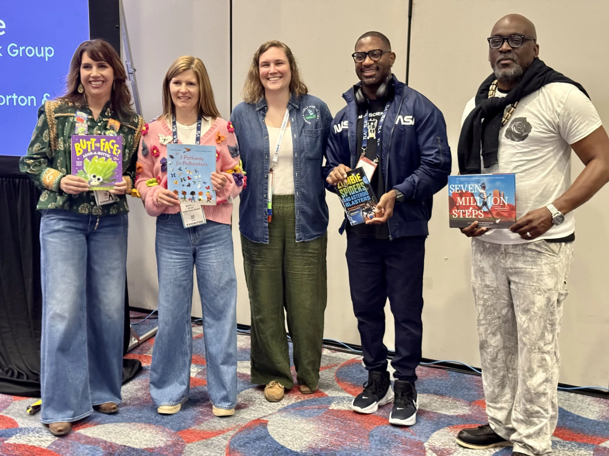 Photo from TxLA showing the following authors holding up their books: Kari Lavelle, Michelle Schaub, Derrick Barnes, and Maynard Okereke.