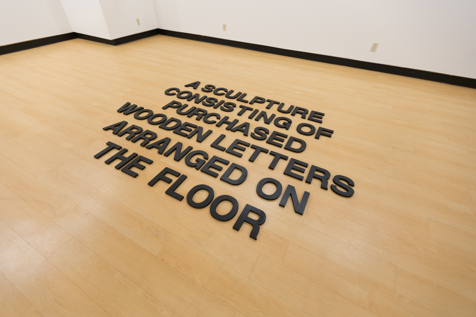    A Sculpture Consisting of Purchased Wooden Letters Arranged on the Floor , 2019  Wood, India ink, and wax Size variable 