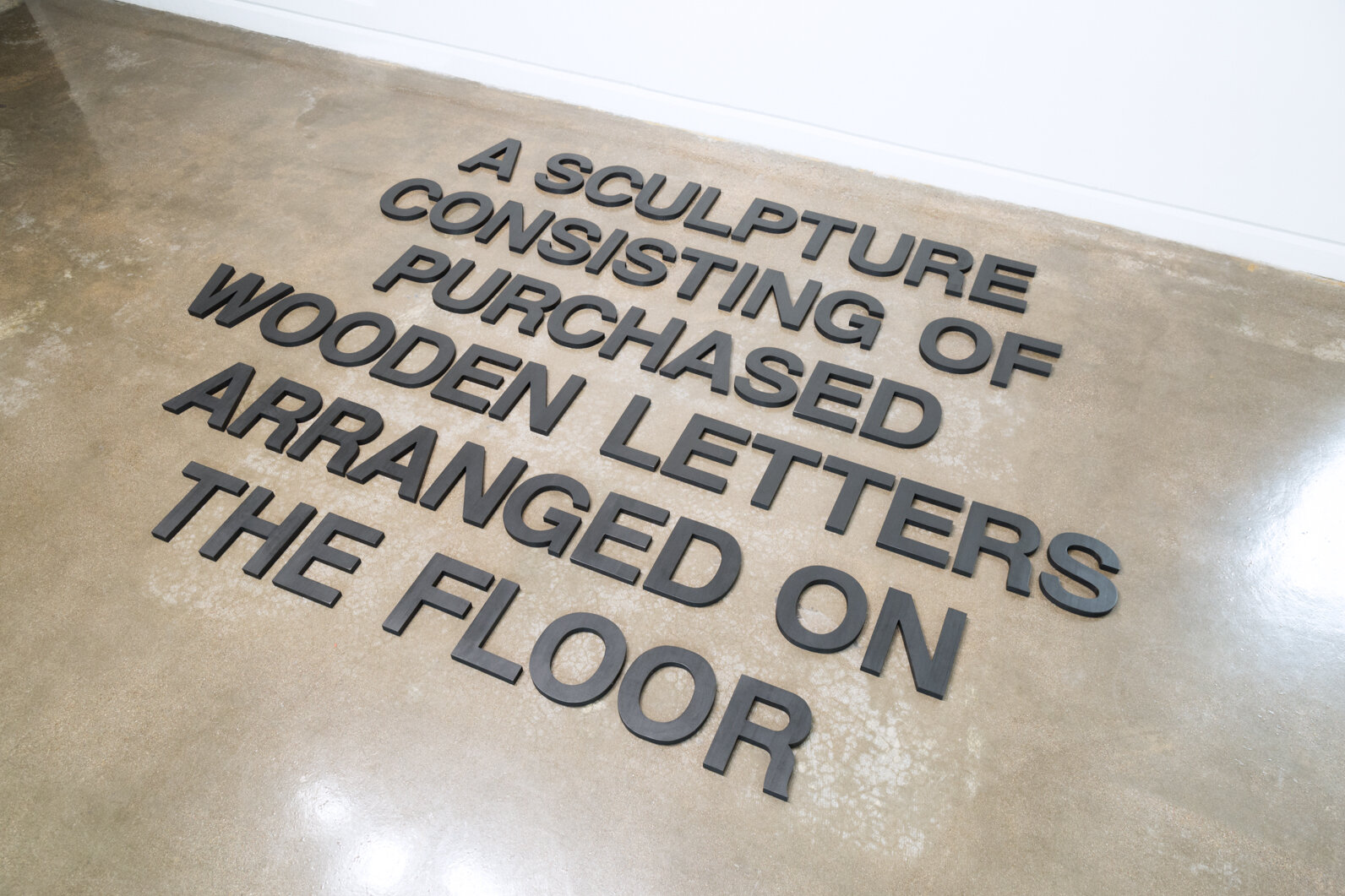    A Sculpture Consisting of Purchased Wooden Letters Arranged on the Floor , 2019  Wood, India ink, and wax Size variable 