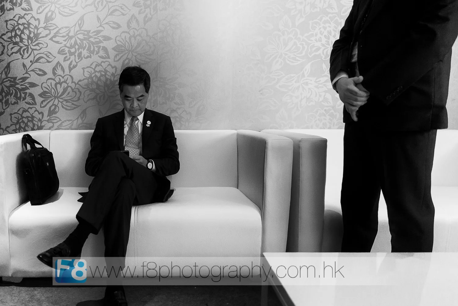 chief executive of hong kong, mr cy leung checks his speech notes before going on stage in front of thousands of ceo's and vvip guests at apec 2015. his bodyguard stands close by.
