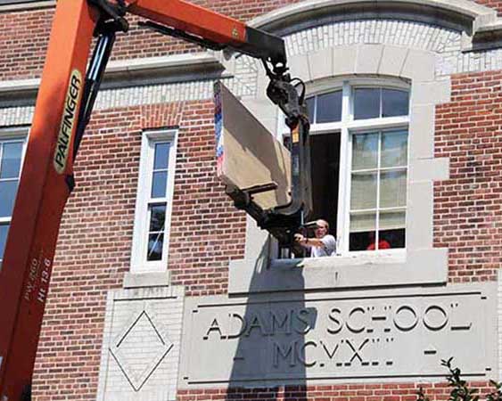Sheetrock for the blackboard project is hoisted in through the math office window.