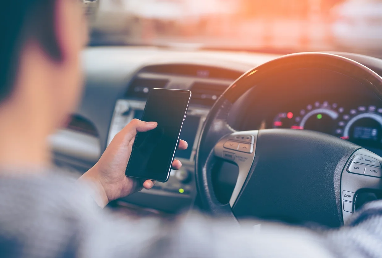 Man using a smartphone while driving a car