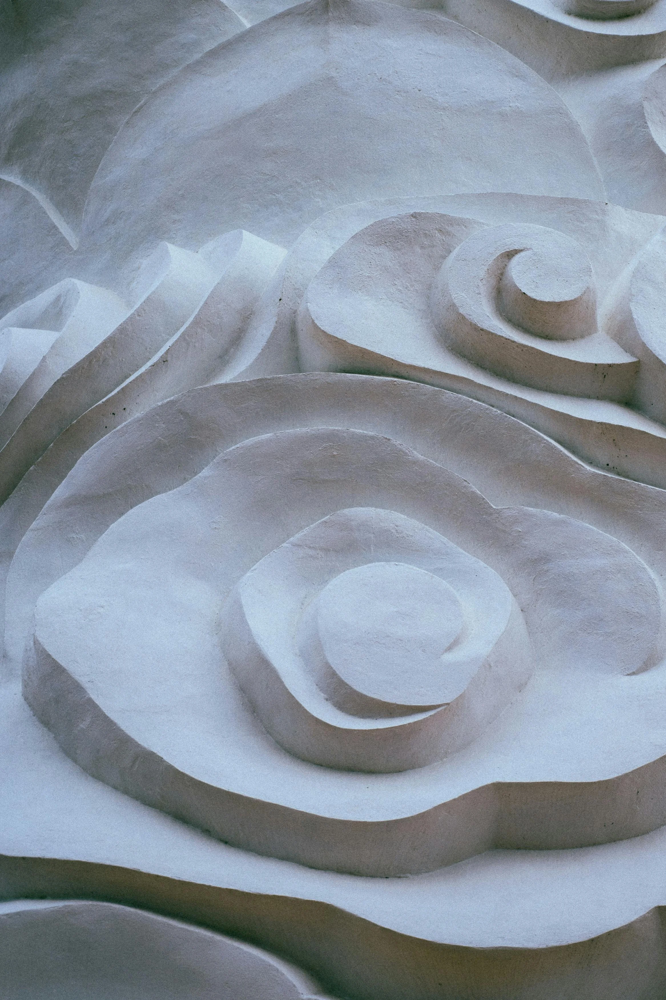 Close-up of a white textured sculpture with swirls and rounded shapes.
