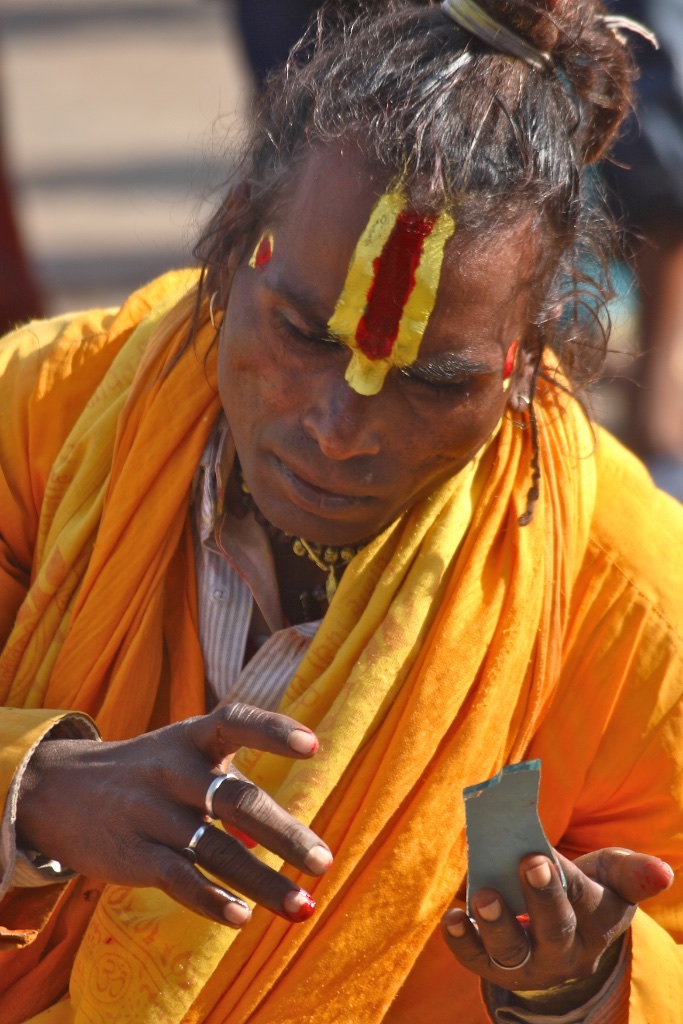 Sadhu makeup with the help of a broken mirror. Orchha, India.