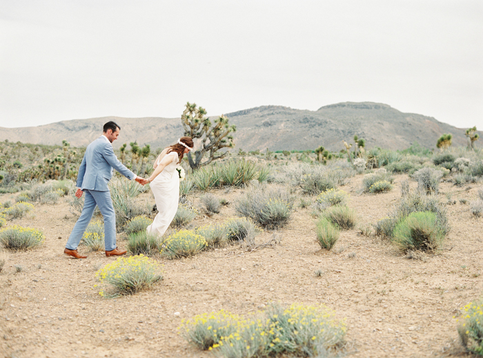 bride and groom walking through las vegas desert wildflower patch