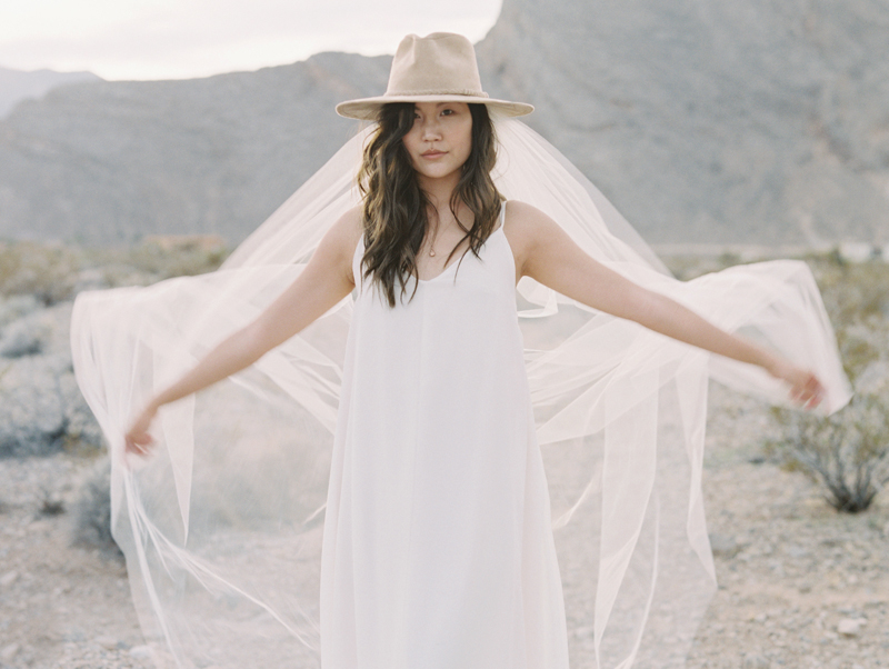 bride wearing veil and cowboy hat in the desert