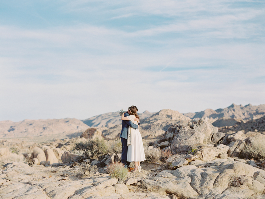 bride and groom hugging each other in the desert