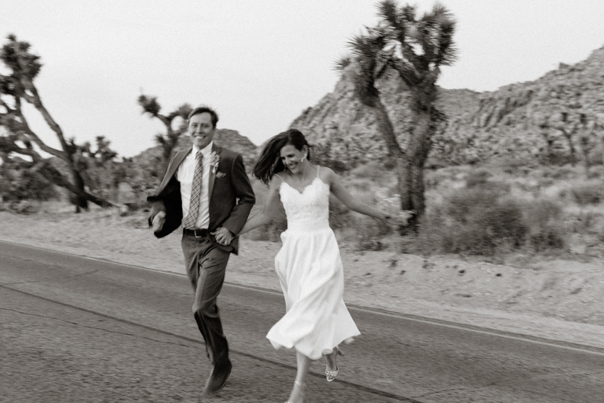 bride and groom running in the street joshua tree national park