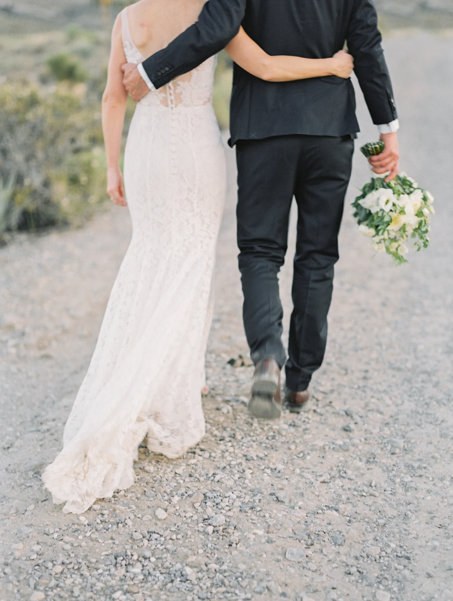 bride and groom walking holding onto each other