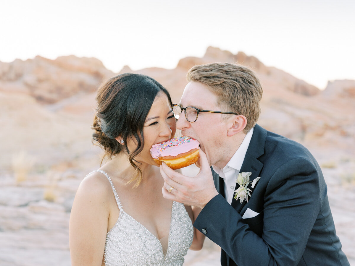 bride and groom eating donuts on their wedding day