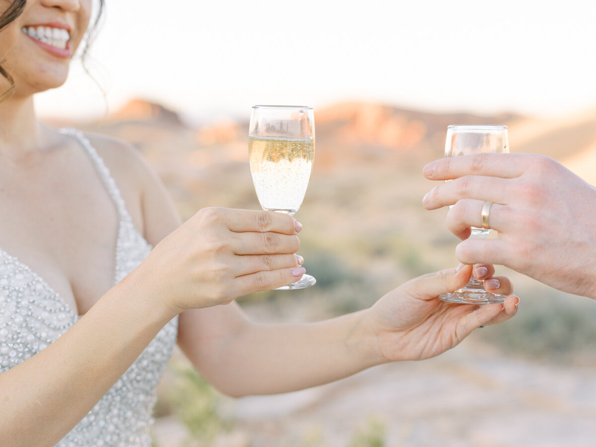 bride and groom drinking champagne in the desert