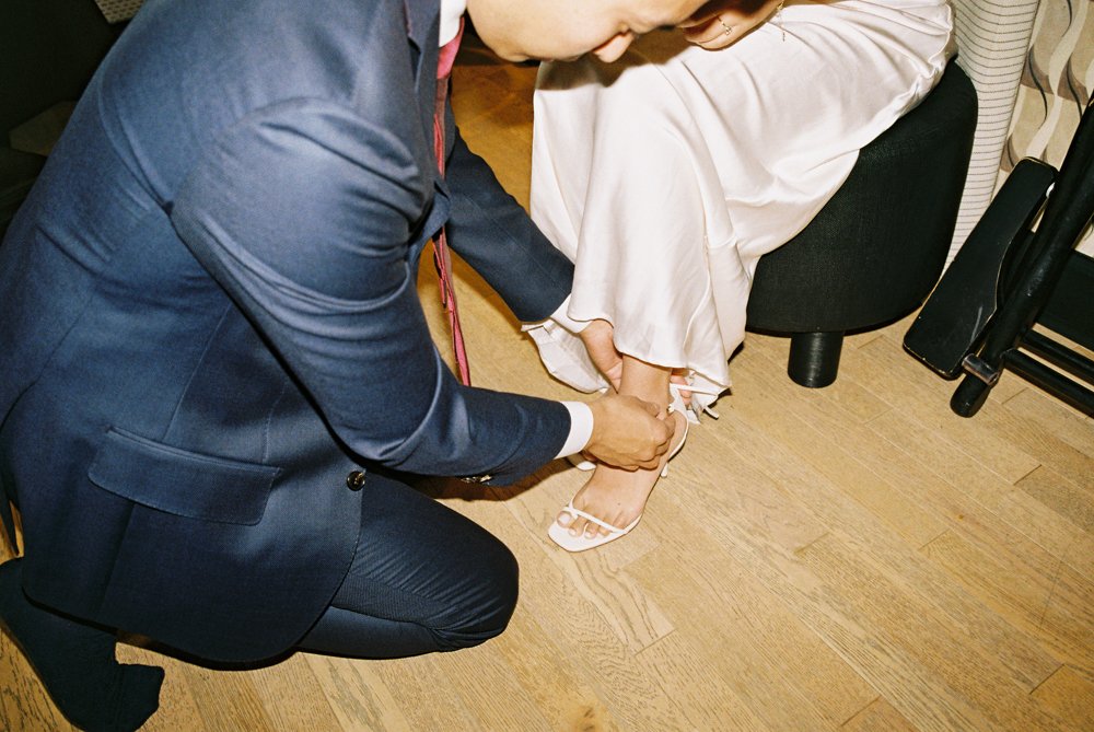 groom helping bride into her shoes