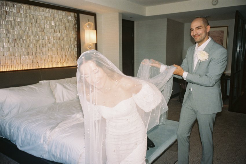 groom putting veil on bride