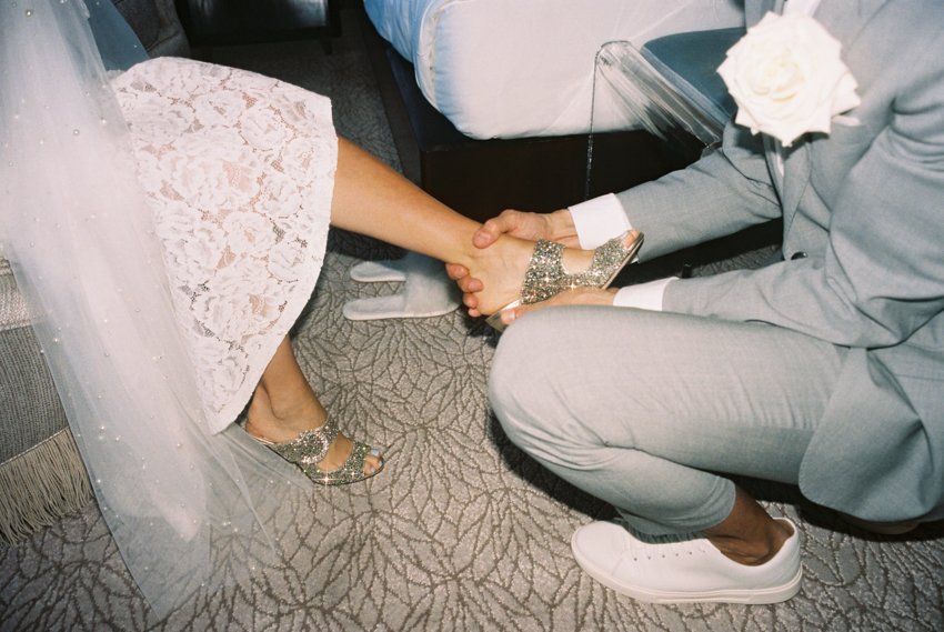 groom putting on brides shoes