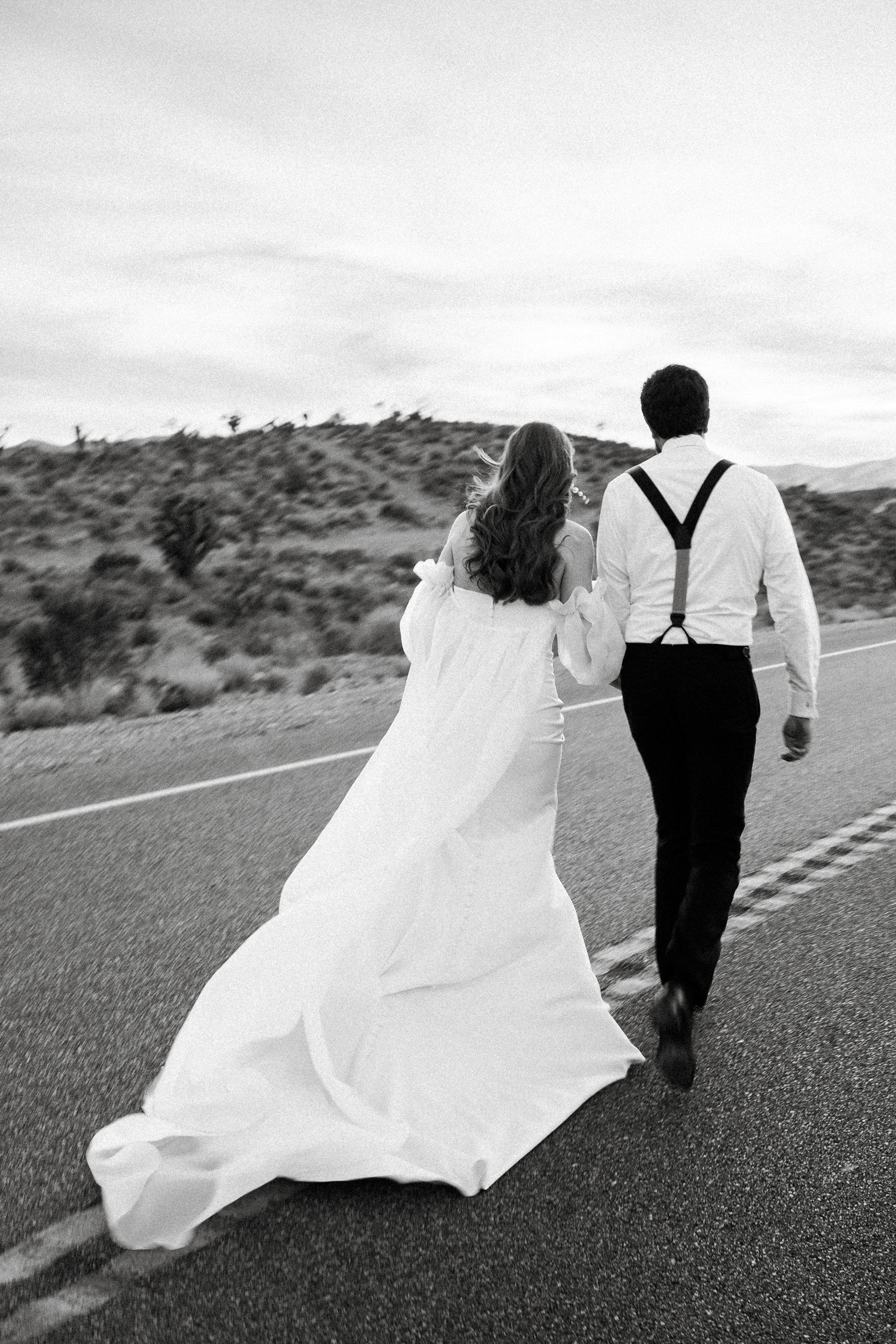 bride and groom running in the middle of the road