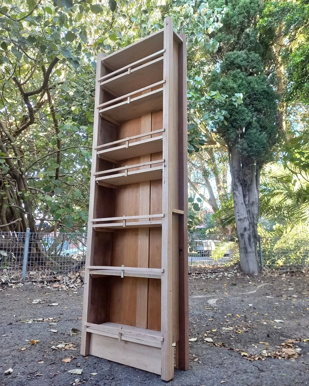 Children planting seedlings in garden trays on a wooden table outdoors, with gardening tools and supplies nearby.