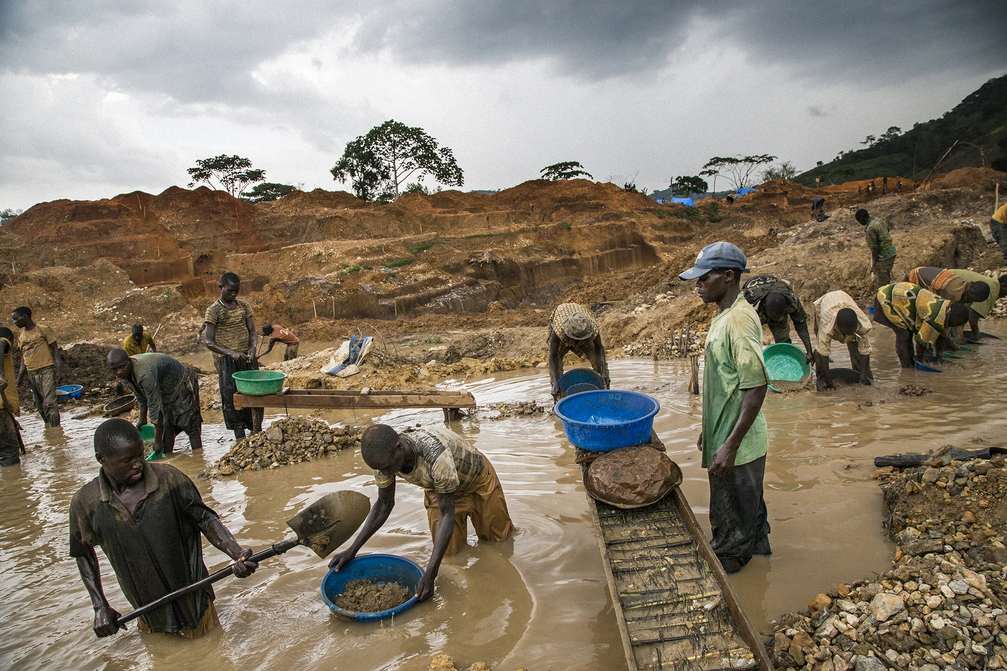 Miners in the mining town of Pluto in Ituri Province extract rock and sand from a large pit which has taken over a year to excavate. Then they filter the crushed rock through towels to extract the gold dust. The miners are made up of many different people from all over Congo who come to seek their fortune.