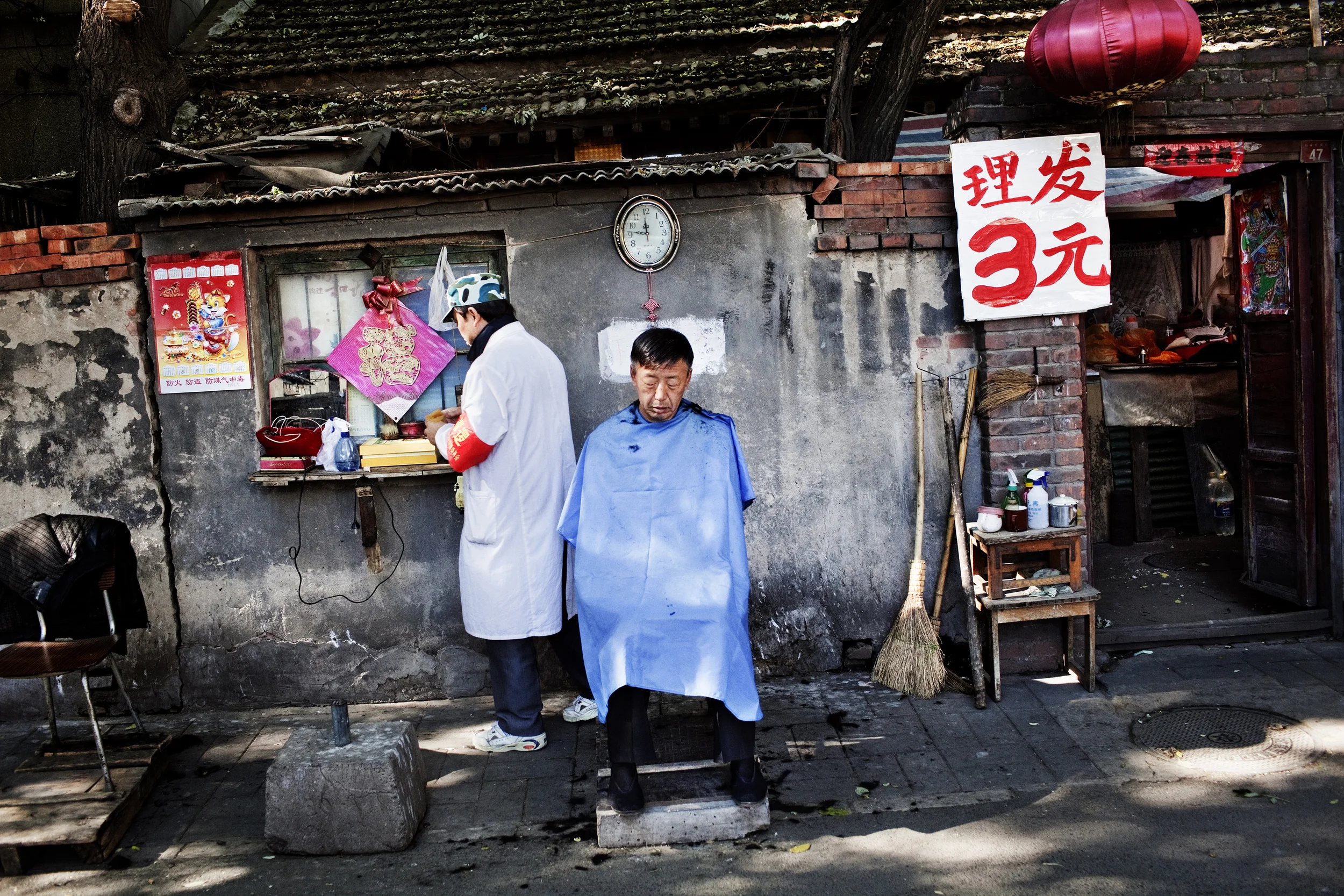 A man has his hair cut in a hutong--one of the hundreds of tree-lined alleys that make up the old city of Beijing. Just 15 years ago, Beijing had thousands of hutongs but most have been leveled to make way for giant property developments backed by wealthy entrepreneurs and Communist Party officials.